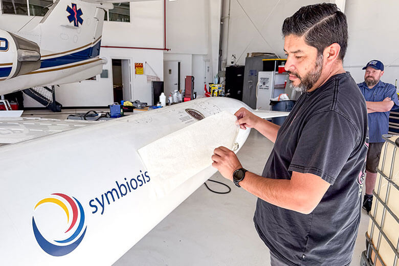 img-air-ambulance-logo-plane-2 a man putting symbiosis sticker on a plane